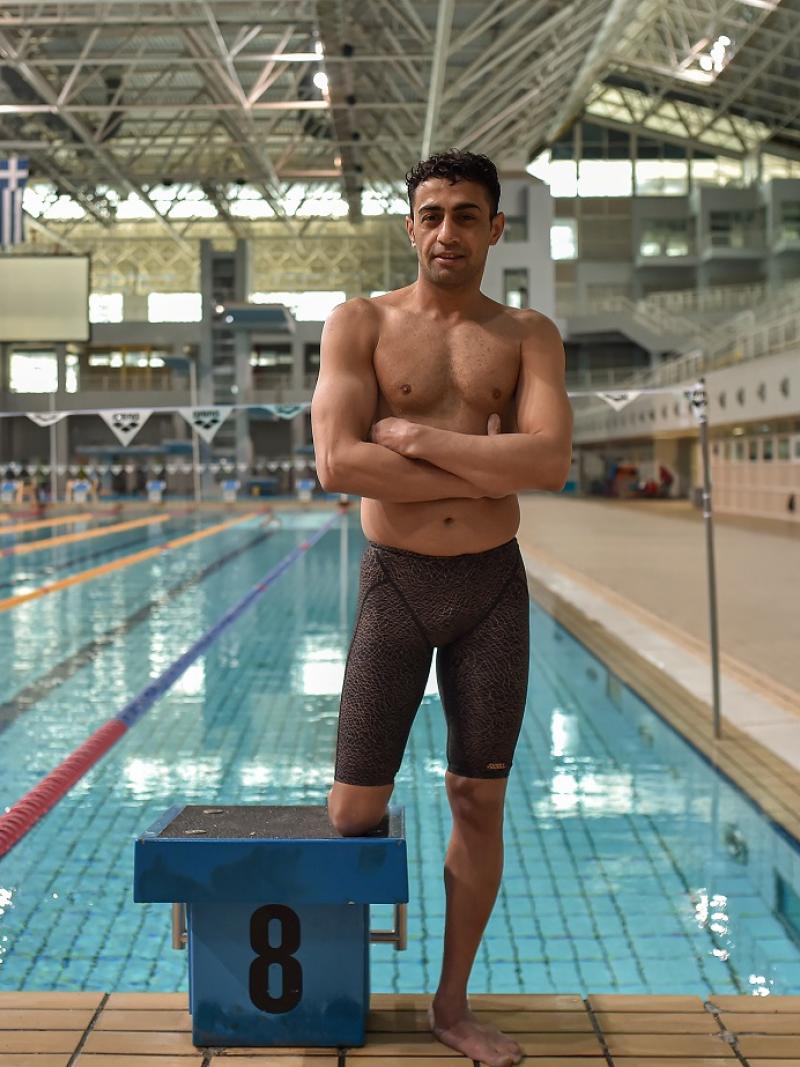 Swimmer Ibrahim Al Hussein posing in front of the pool while wearing his swimsuit
