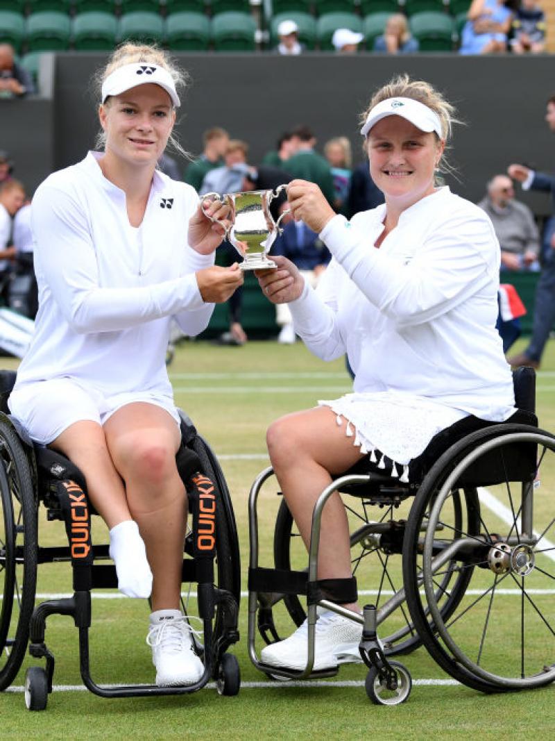 Two women in wheelchairs holding Wimbledon trophy together