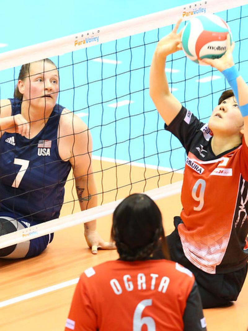Chinese player sets the volleyball as USA opponent watches on the other side of the net
