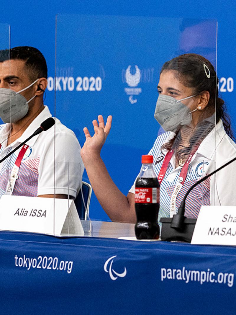A man and a woman in a press conference wearing face masks