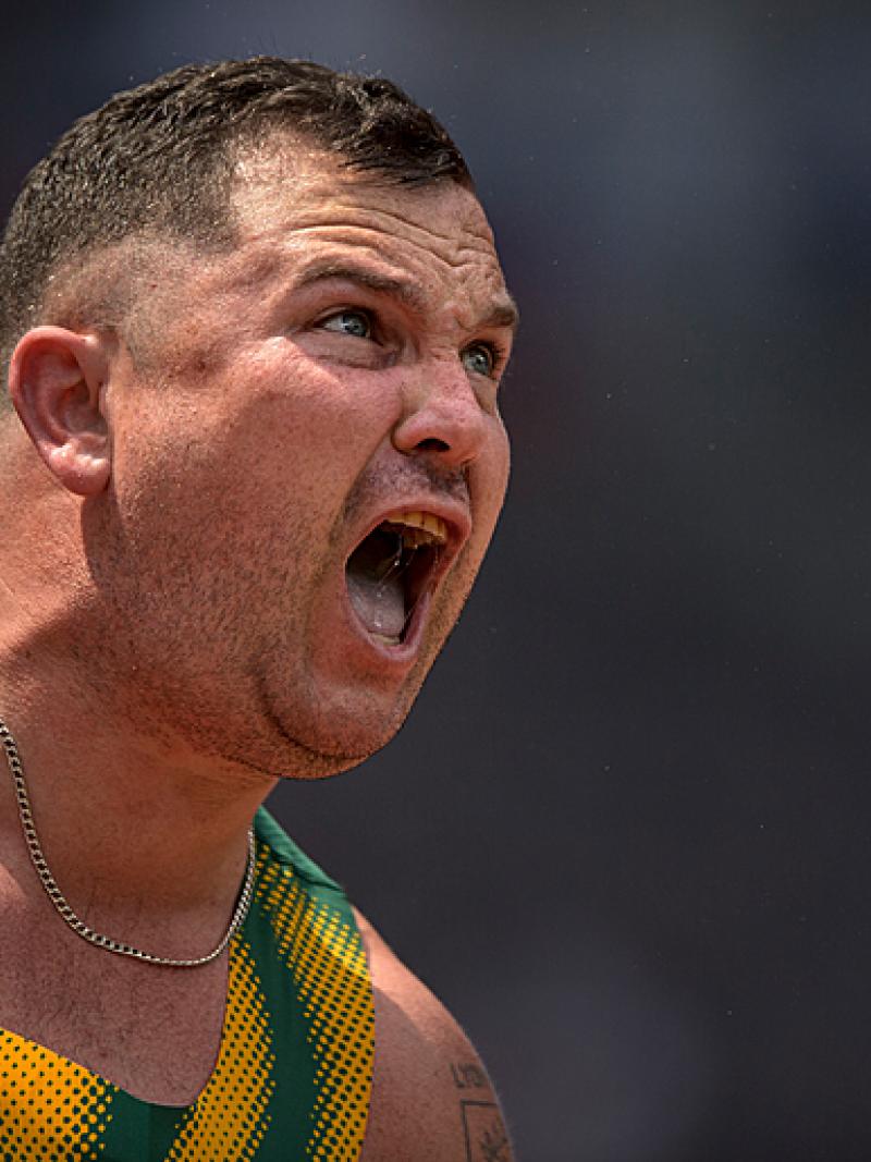 Reinhardt Hamman in a green vest with a gold chain shouts with exertion