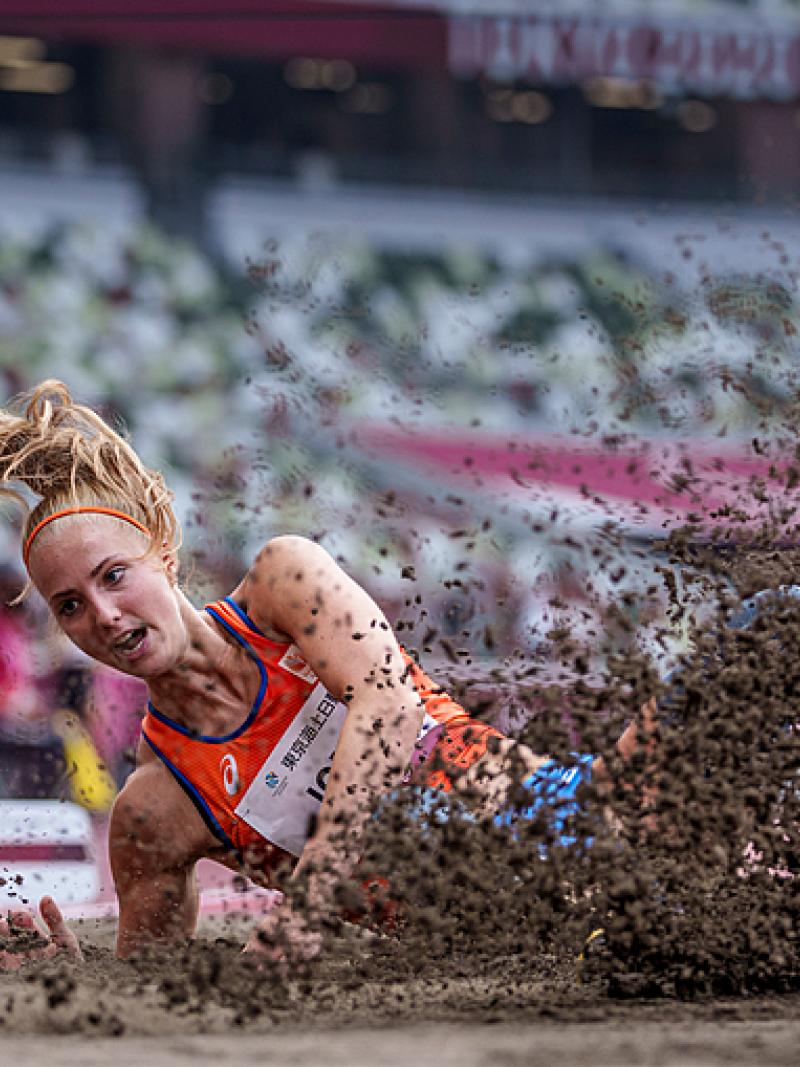 A woman falling in a sand pit in a long jump competition