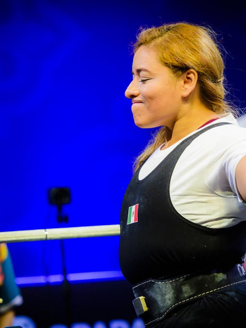 A woman stretching her arms in front of a bench press in a powerlifting competition