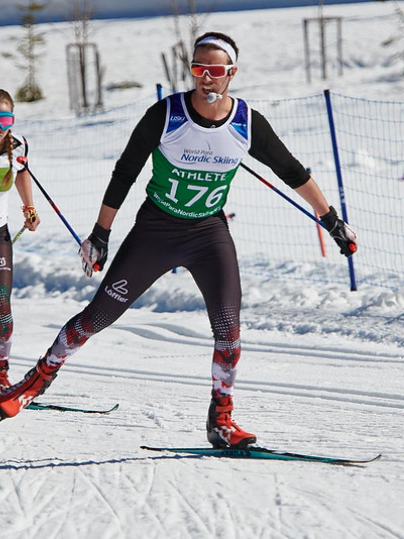 A female Para cross-country skier following her male guide during a competition