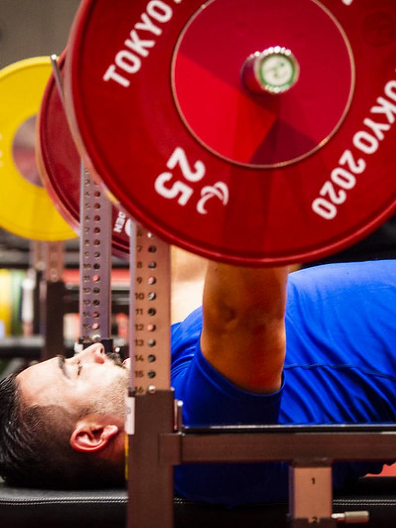 A man with a blue shirt practicing on a bench press