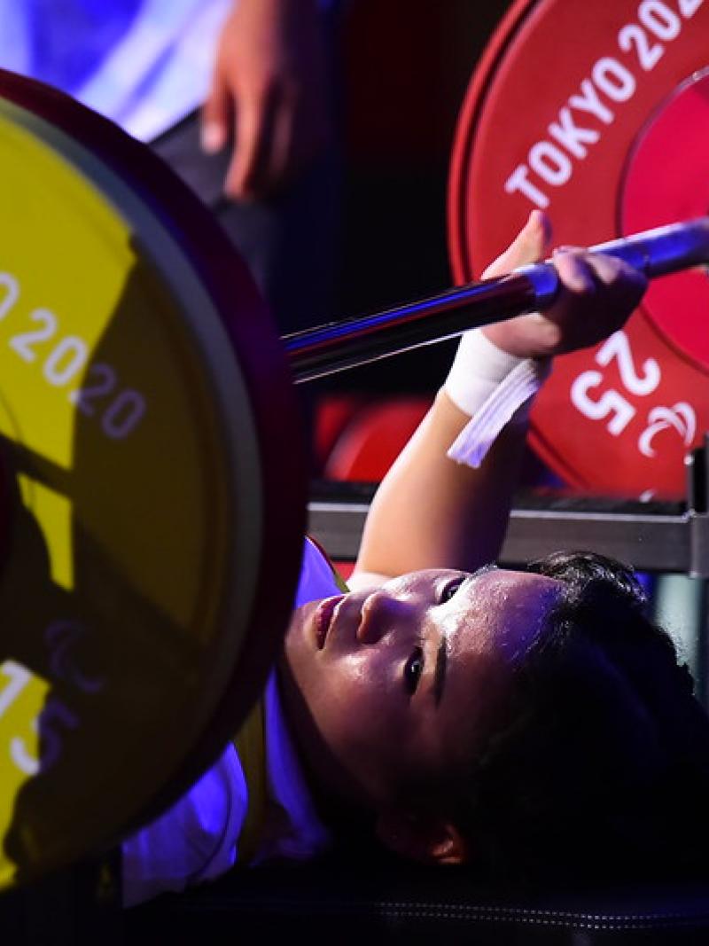 A woman preparing to lift the bar on a bench press competition