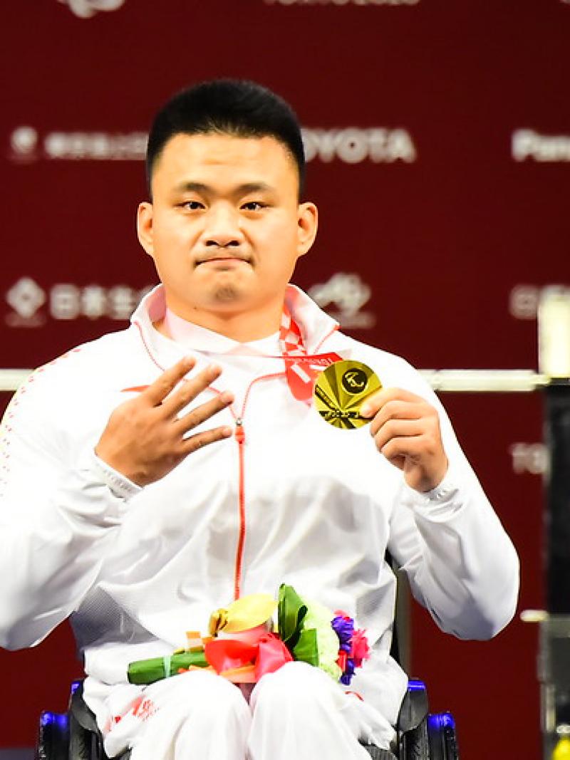 A man showing his medal and four fingers in a hand