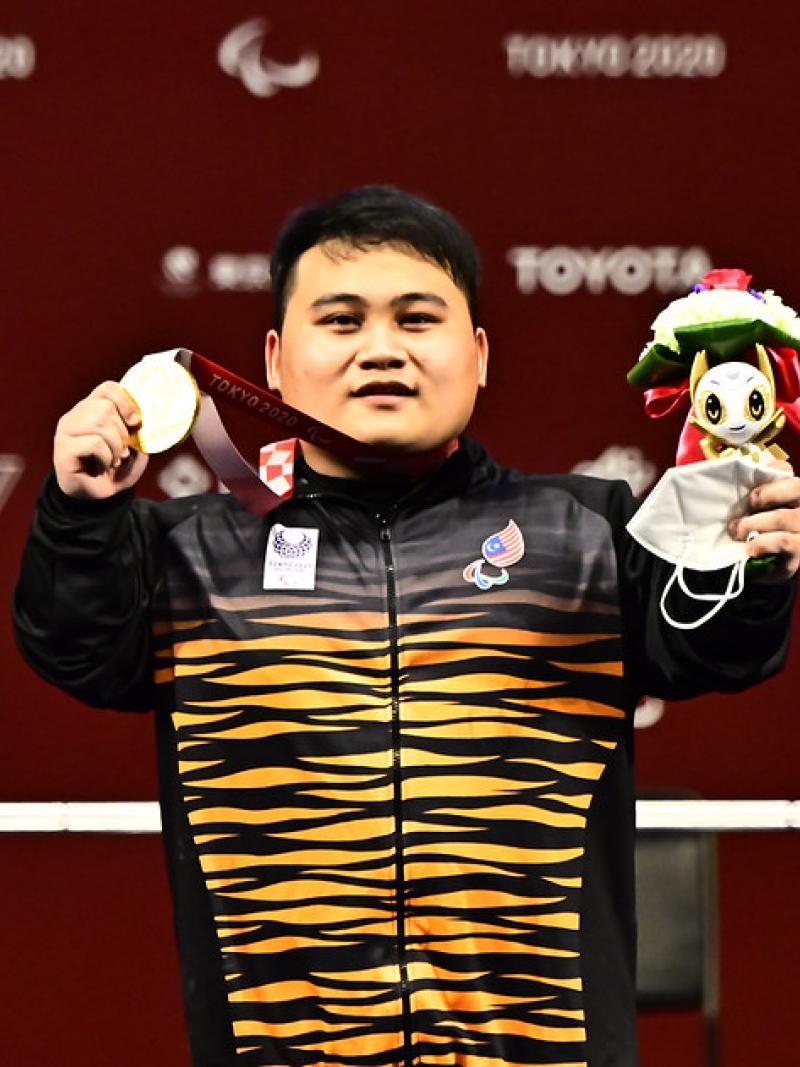 Bonnie Bunyau Gustin holding his gold medal and mascot