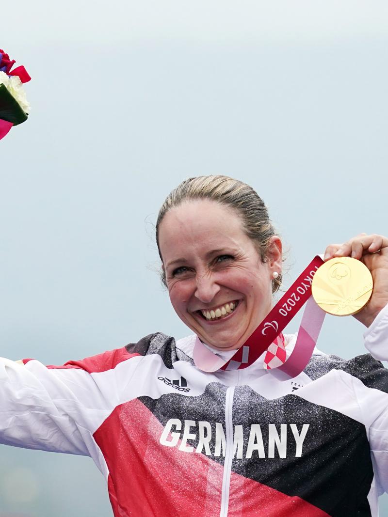 German cyclist Annika Zeyen on the podium holding the gold medal with a smile from ear-to-ear