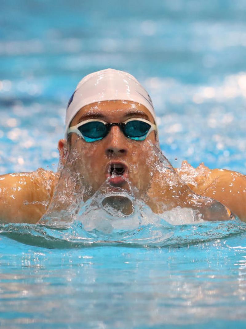 A man swims in the pool with the goggles and swimming cap