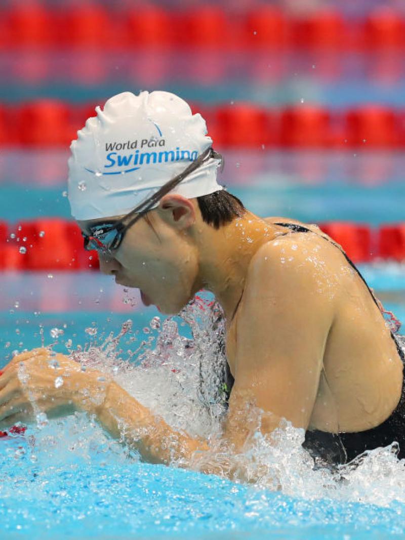 A female swimmer in the pool swimming in the breaststroke style