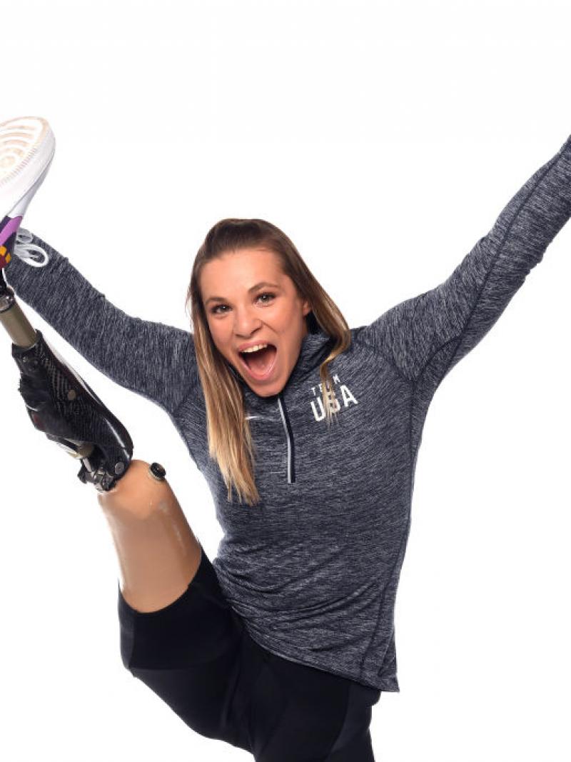 A woman stretching her prosthetic leg and smiling