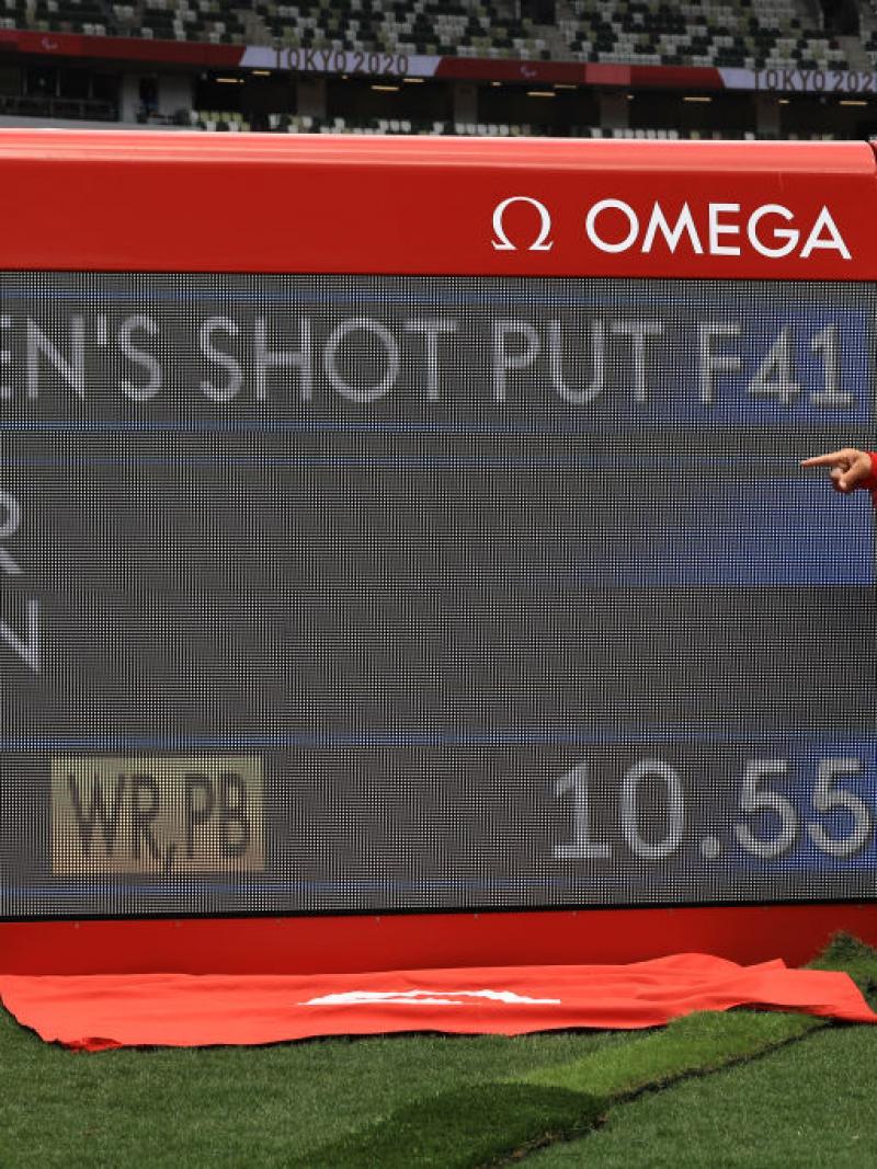 A woman pointing at a screen showing her world record mark in a stadium