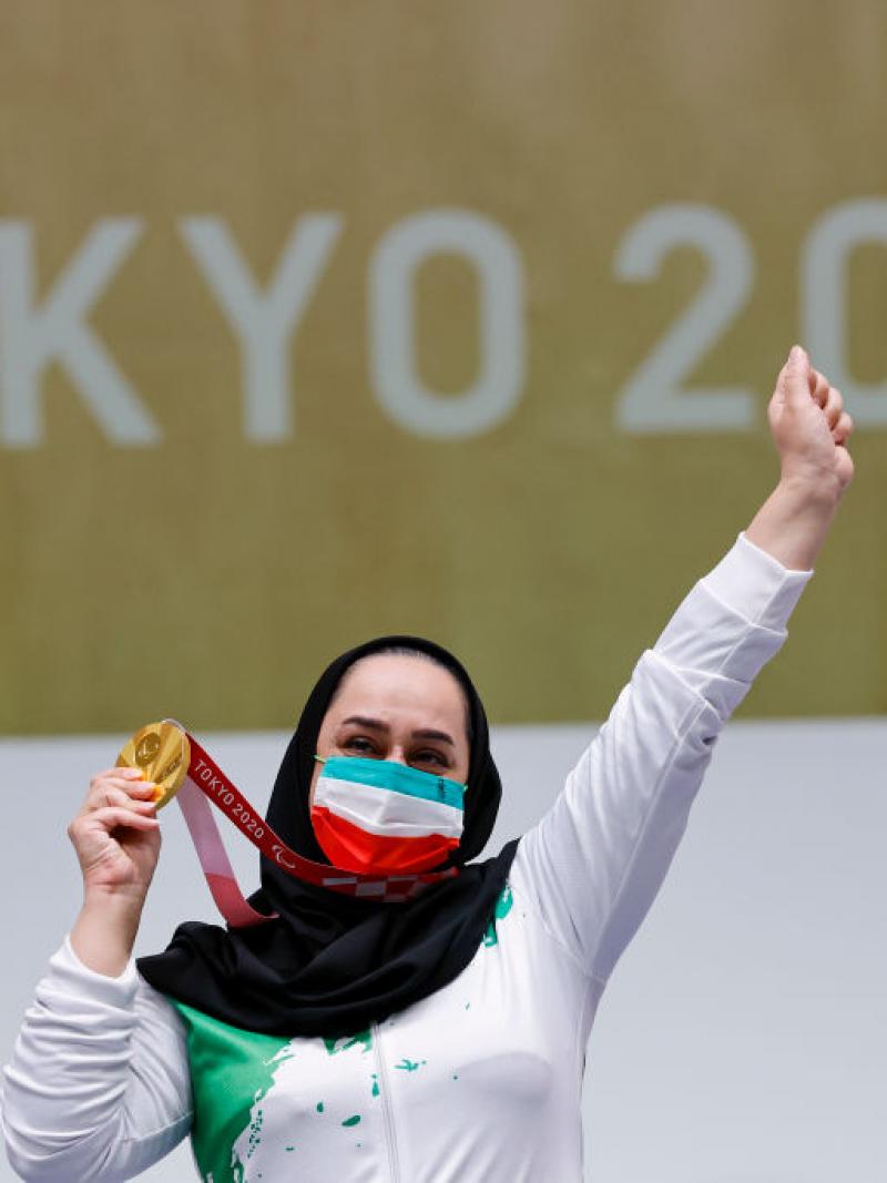 A woman celebrating with her gold medal in front a Tokyo 2020 banner
