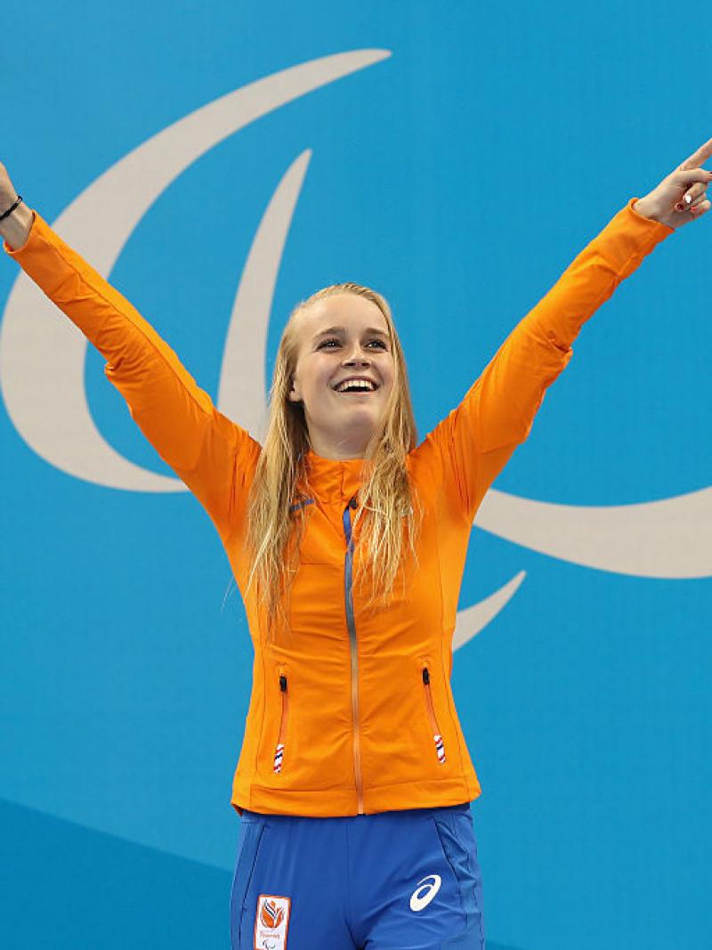 A woman with two raised hands, smiling on the podium