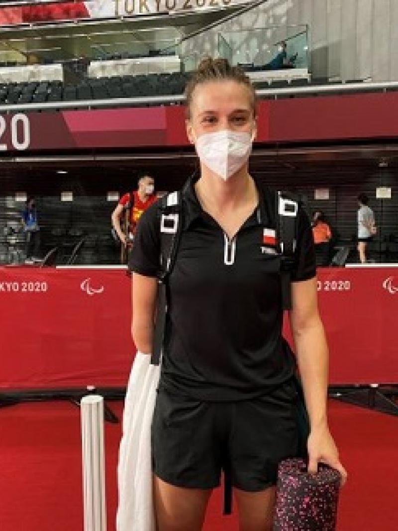 Wearing a white mask and black top and shorts, Natalia Partyka smiles in the press mixed zone