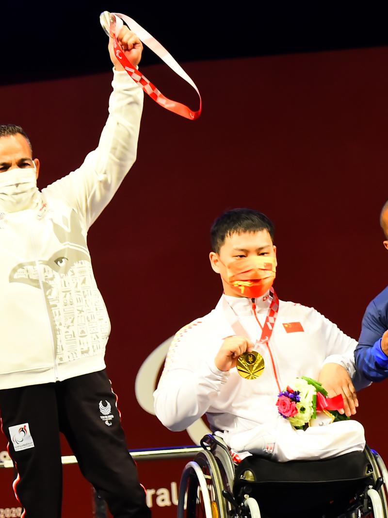 Three men showing their medals on a stage
