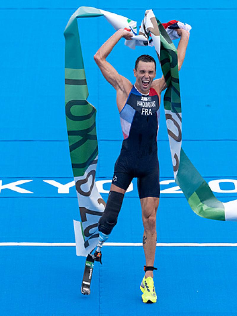Male triathlete celebrates crossing finish tape