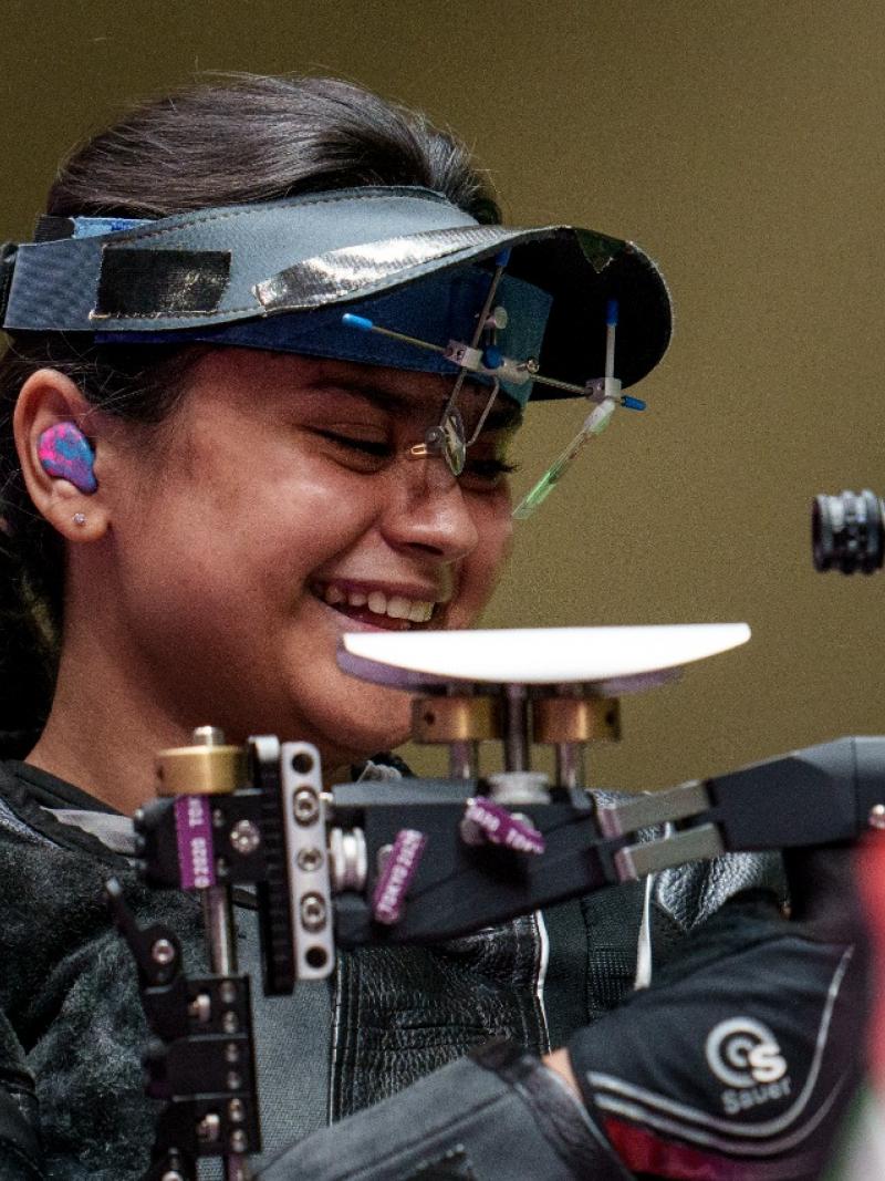 Female Indian shooting athlete smiles