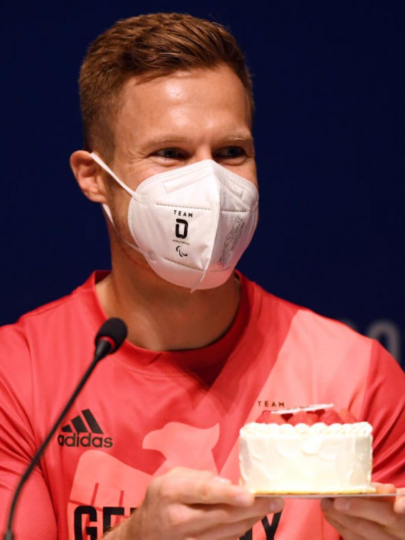 Man with mask on accepts birthday cake