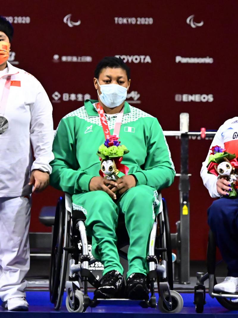 Three women posing for photos on the podium with their medals