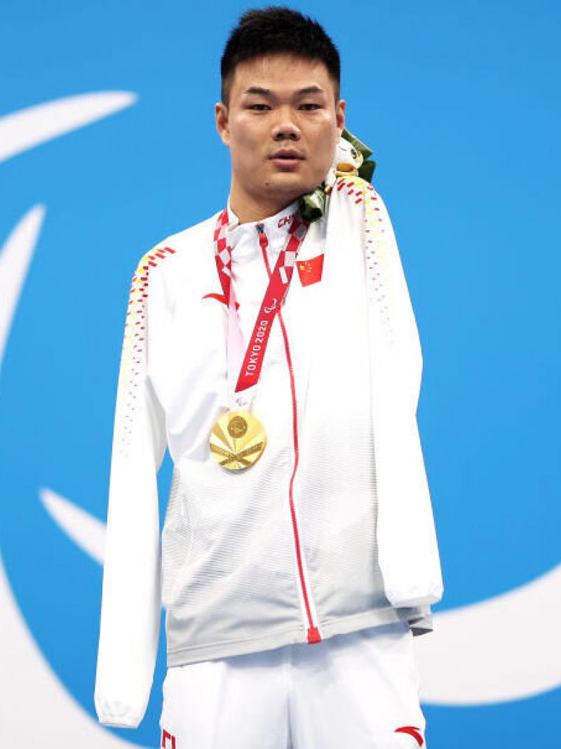 A man poses with a gold medal around his neck
