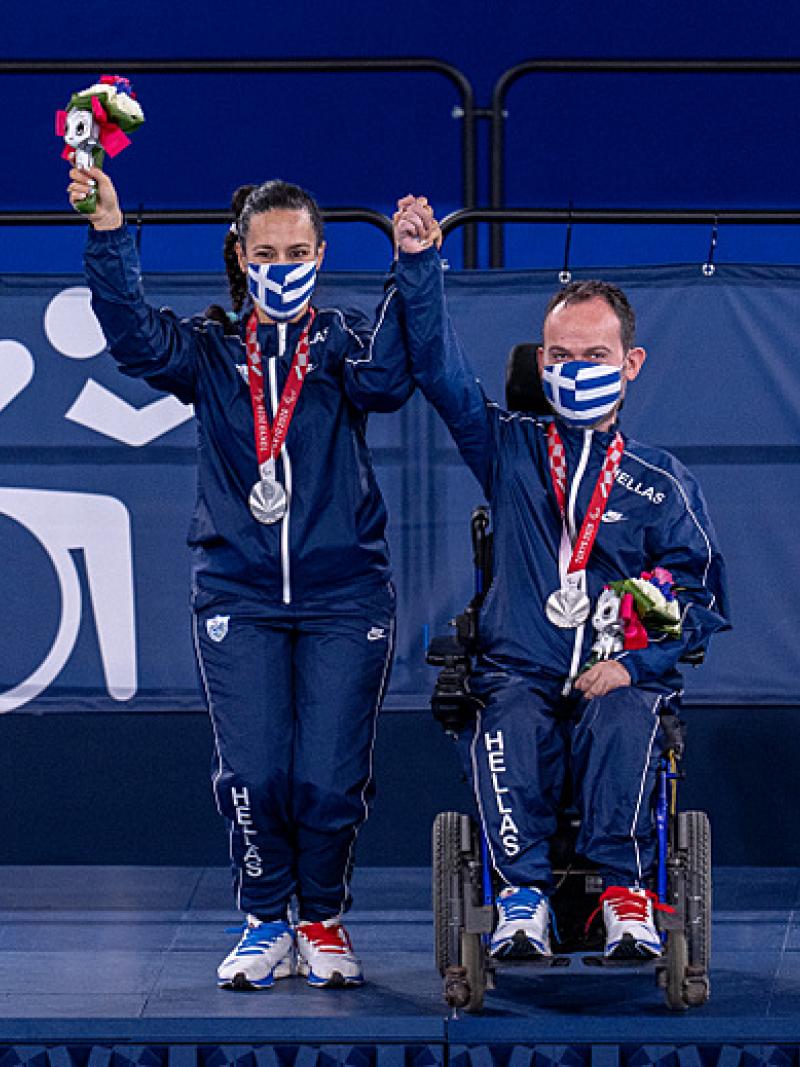 Grigorios Polychronidis with his wife and assistant hold up their hands to celebrate their silver medals 