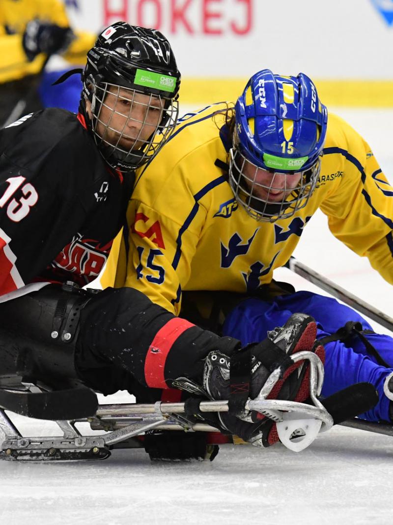 Two Para ice hockey players on sleds battling to get the puck