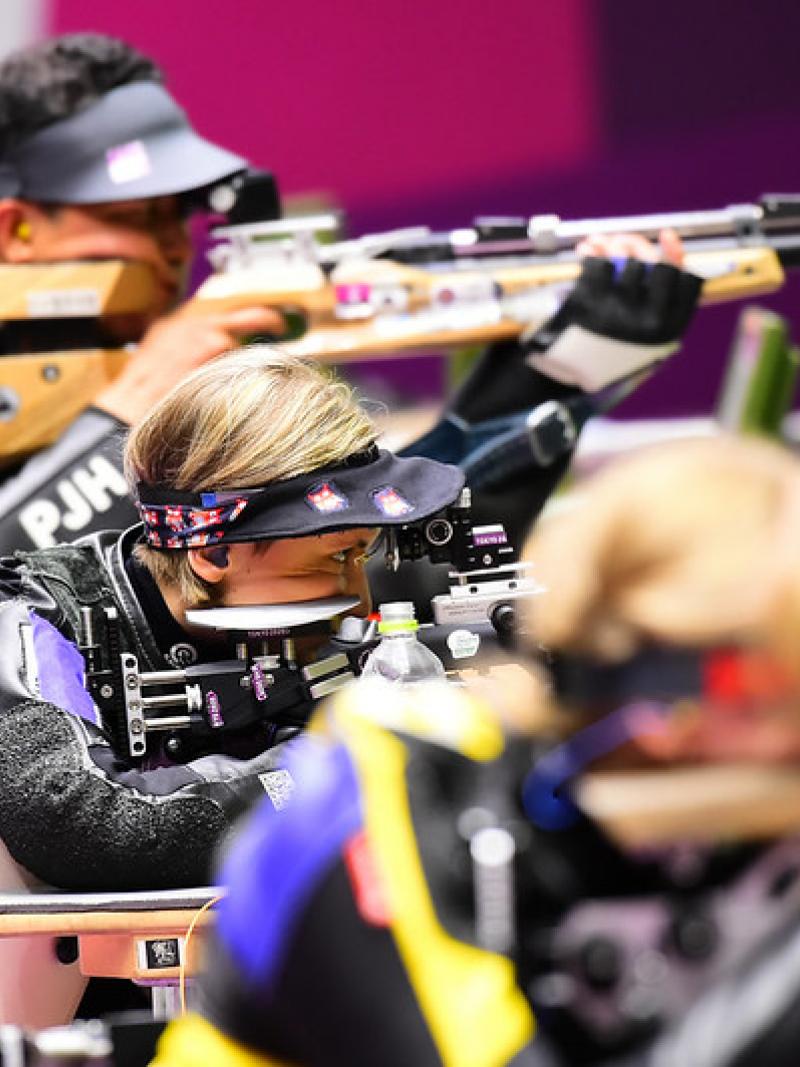 A woman competing in a shooting rifle competition between a male and a female shooter
