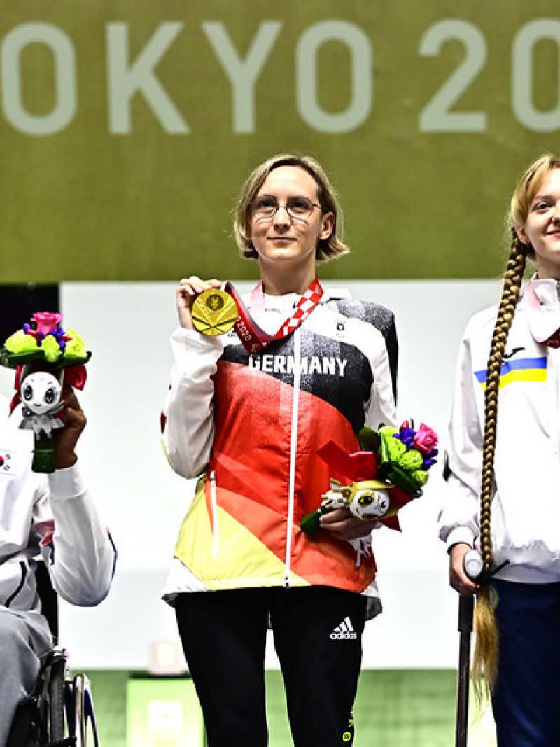 A man in a wheelchair standing next to two women on a podium