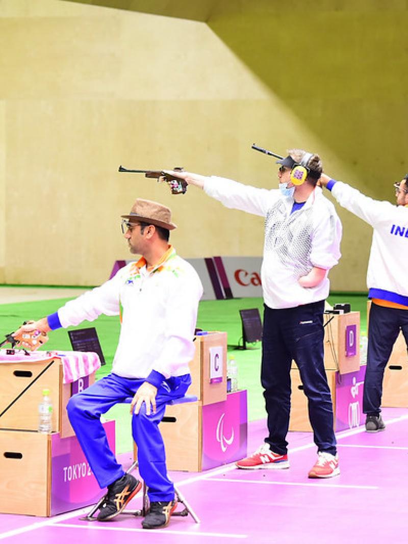 Three male pistol shooters competing in a shooting range