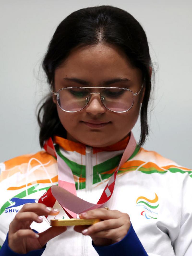 A young woman looking at her gold medal