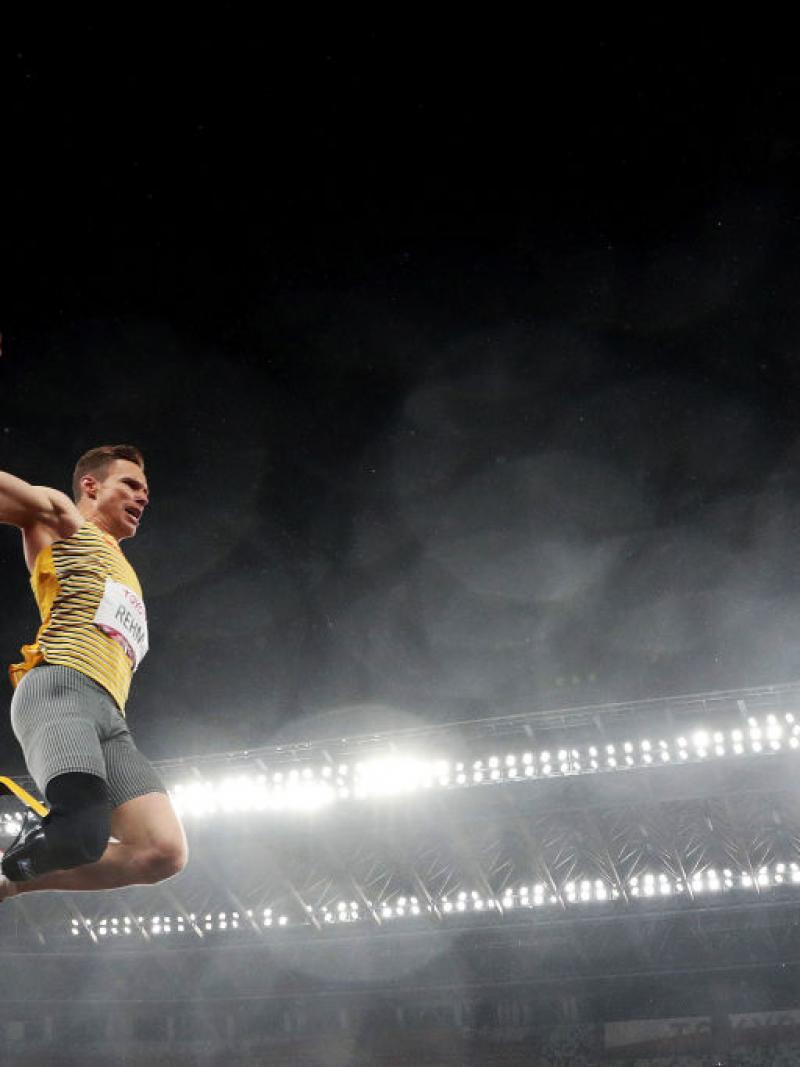 A man with a prosthetic leg jumping in a stadium