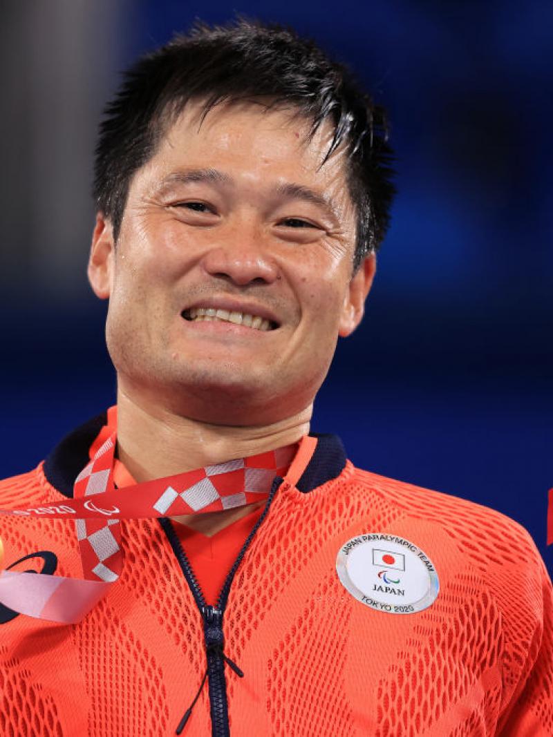 Shingo Kunieda holds his gold medal and mascot on podium
