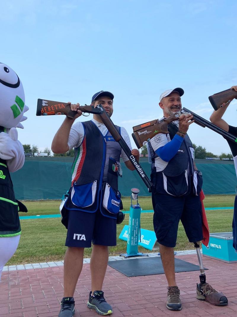 Three men standing with their shotguns near a person dressed as a mascot cat in a shooting range