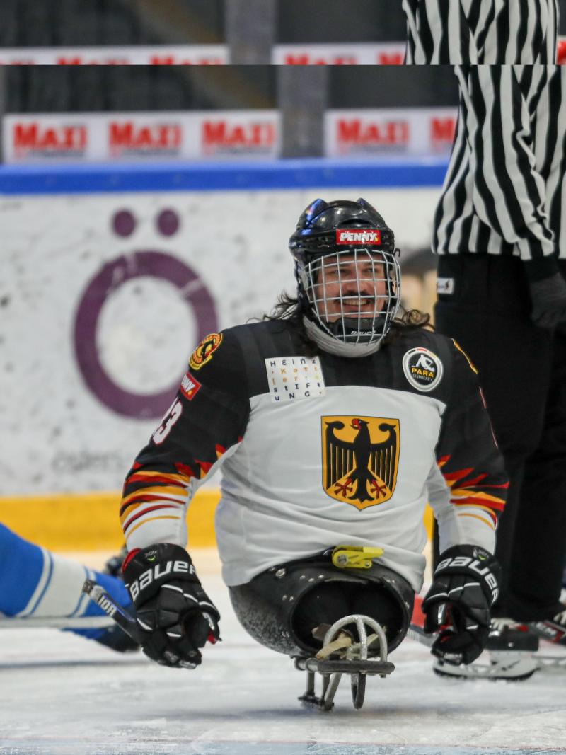 A man on a sled holding two sticks and smiling