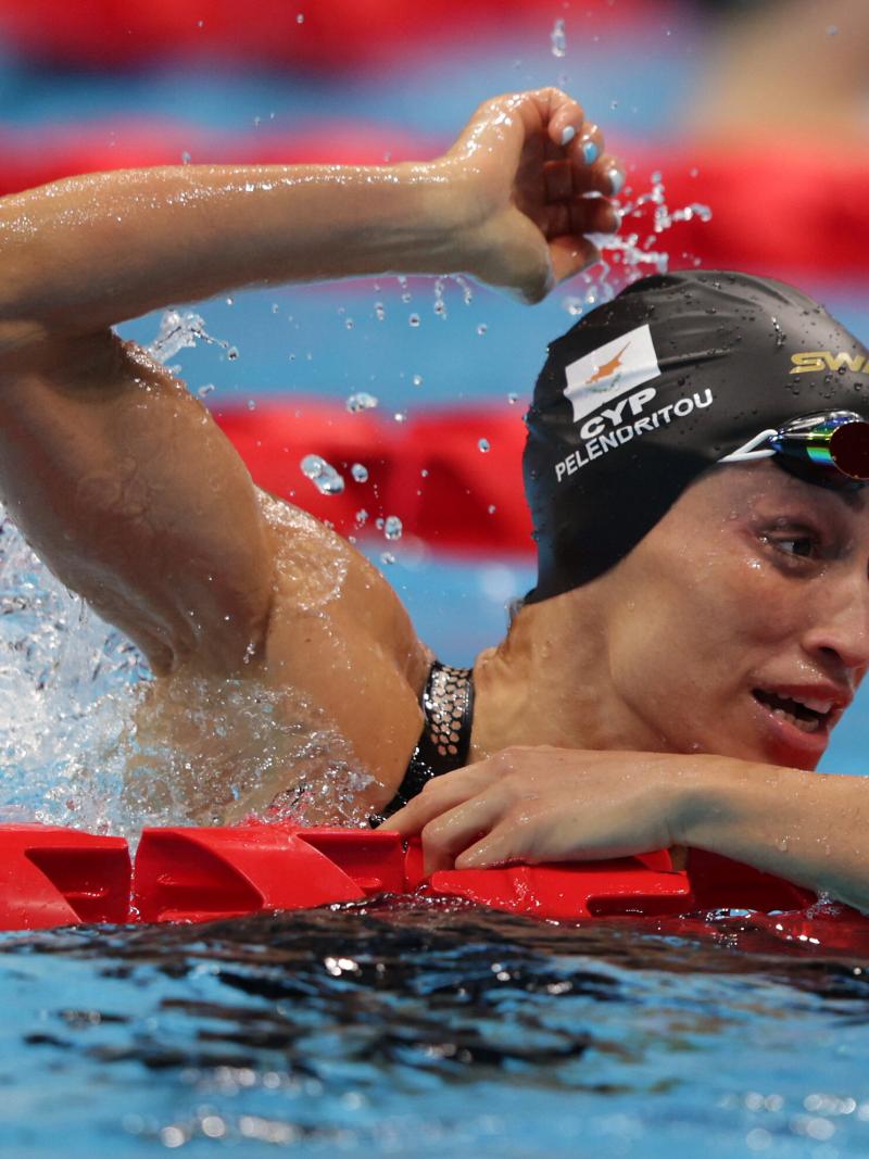 A woman celebrates in the pool with the right arm held high
