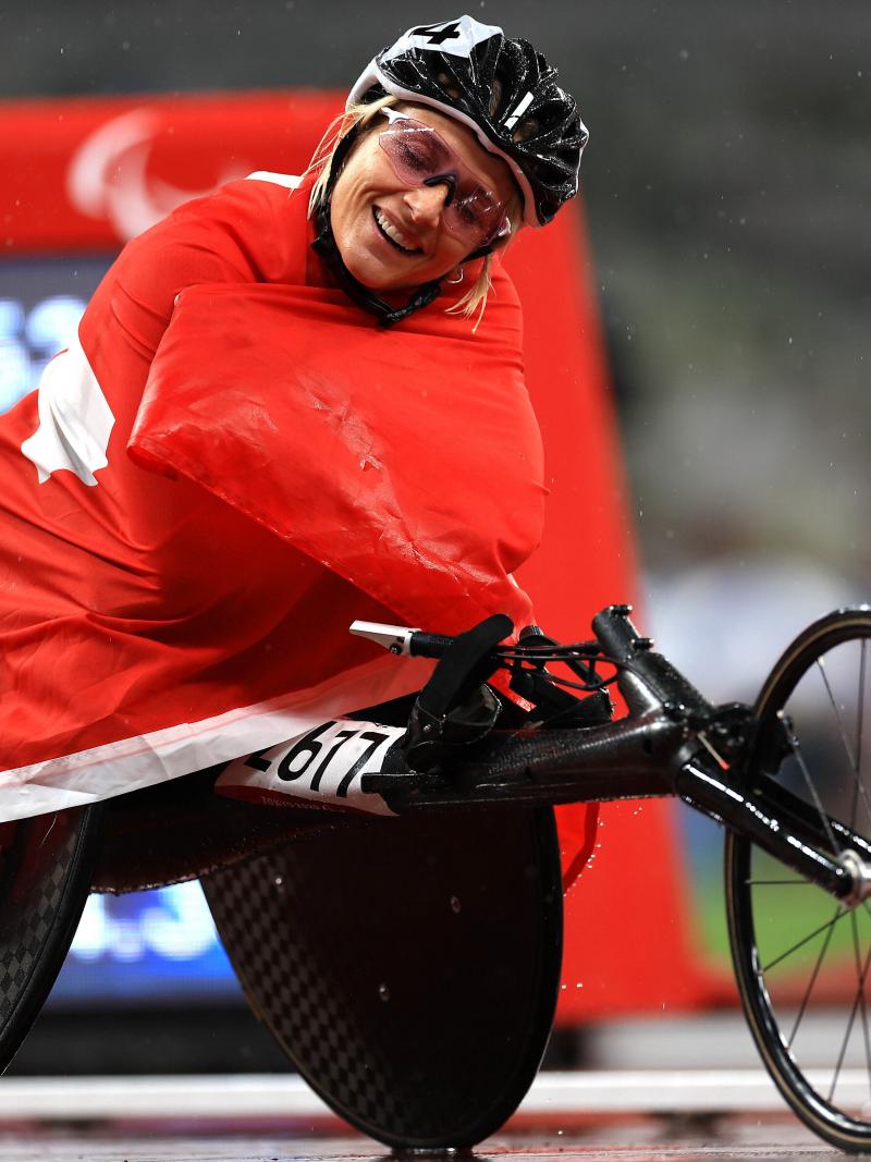 A woman sitting in a wheelchair wrapped around with the Swiss flag
