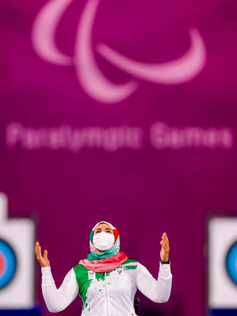 Iranian woman with mask puts hands in air and looks to sky