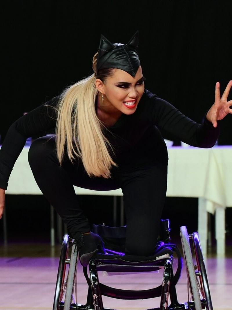 A woman dressed up in a cat performs in a wheelchair during a Para dance sport competition