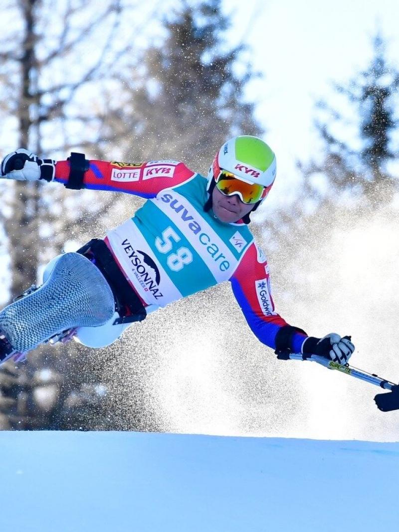 A man competes in Para Alpine skiing on a monoski on a sunny day