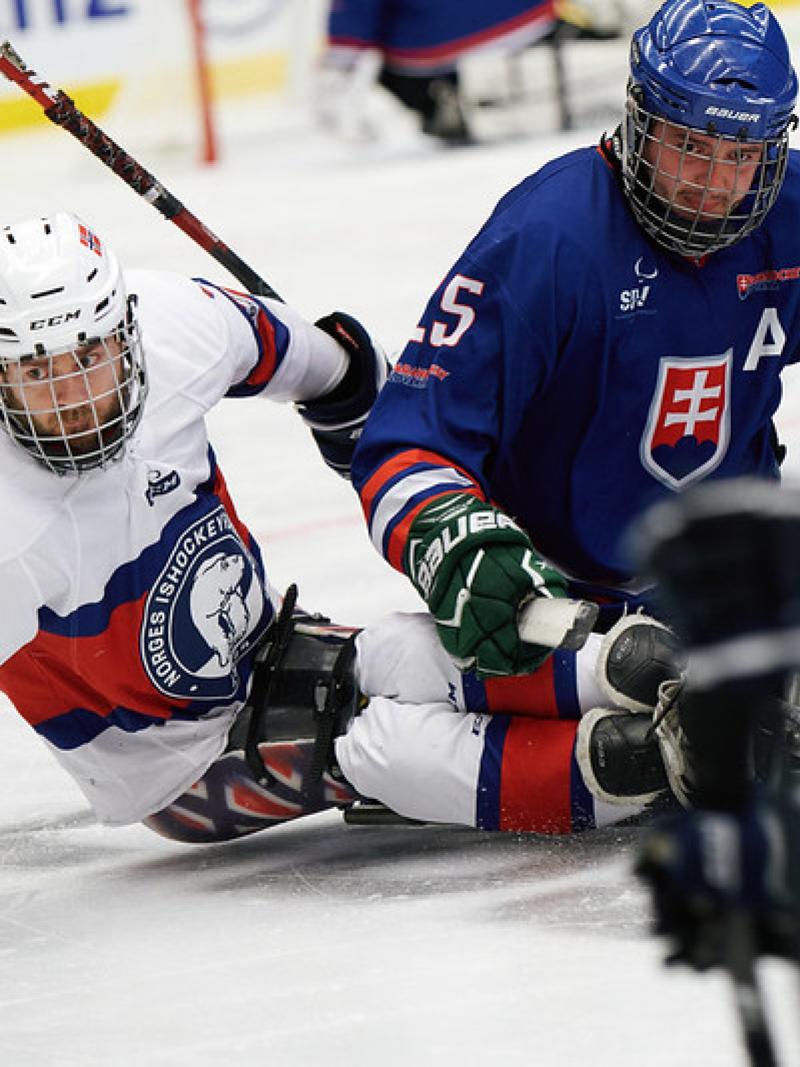 Two male Para ice hockey players chasing the puck 