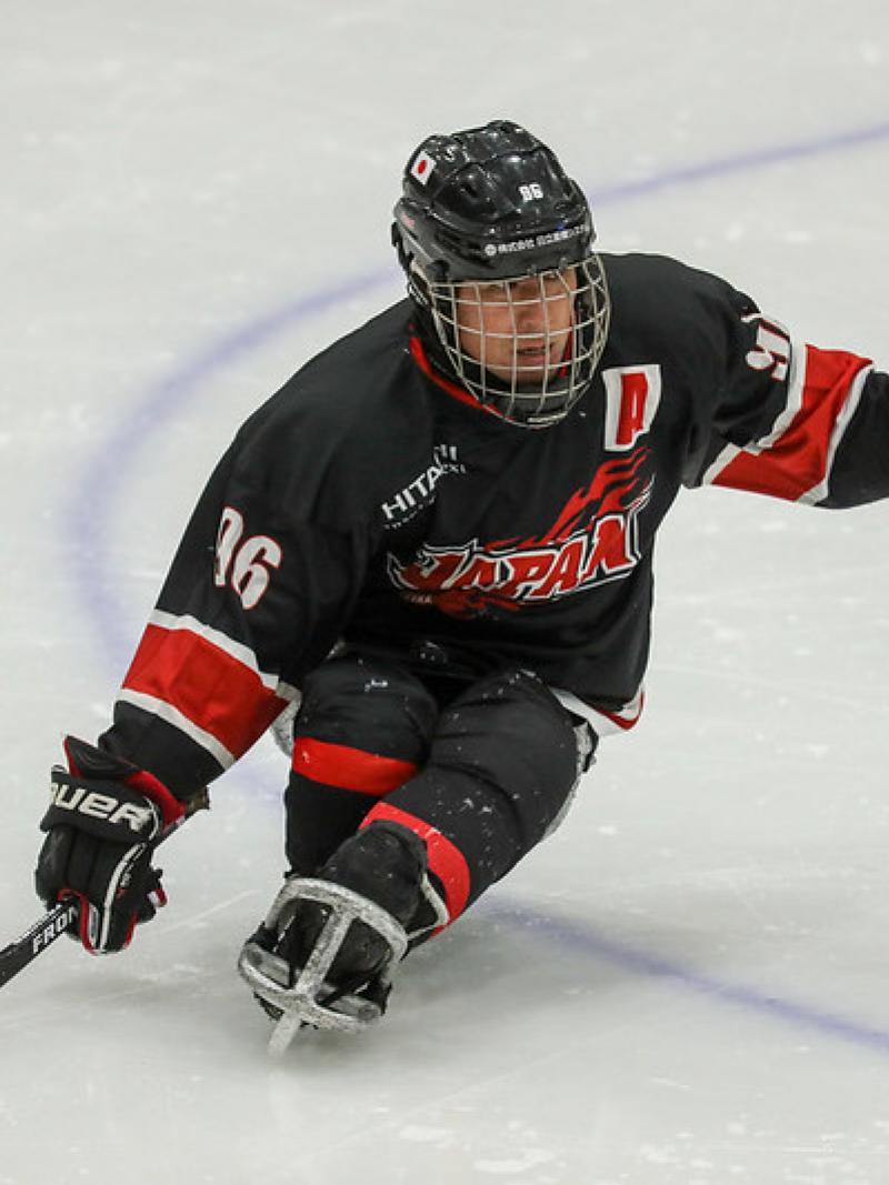 A male Para ice hockey player on ice with the Japanese uniform
