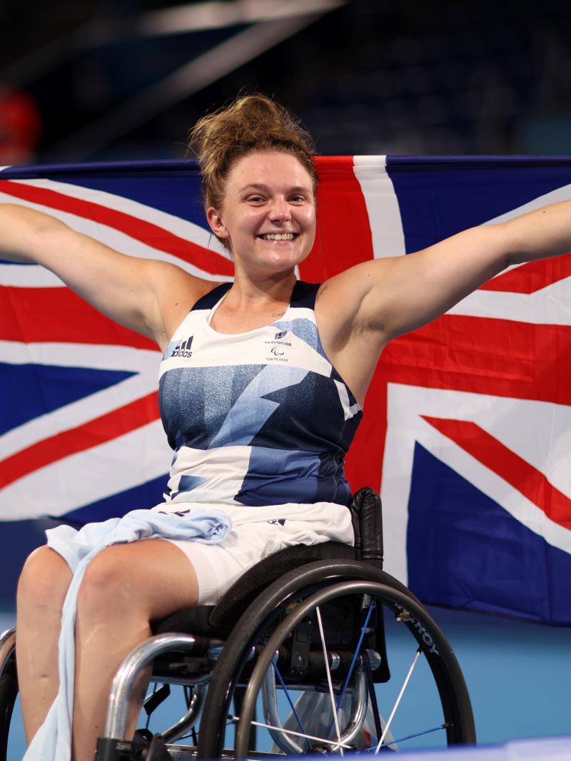 Jordanne Whiley smiles to the camera while holding the British flag