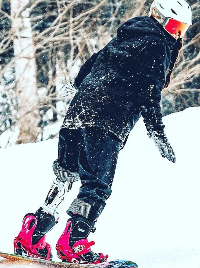 A female Para snowboarder with a prosthetic leg riding in the snow