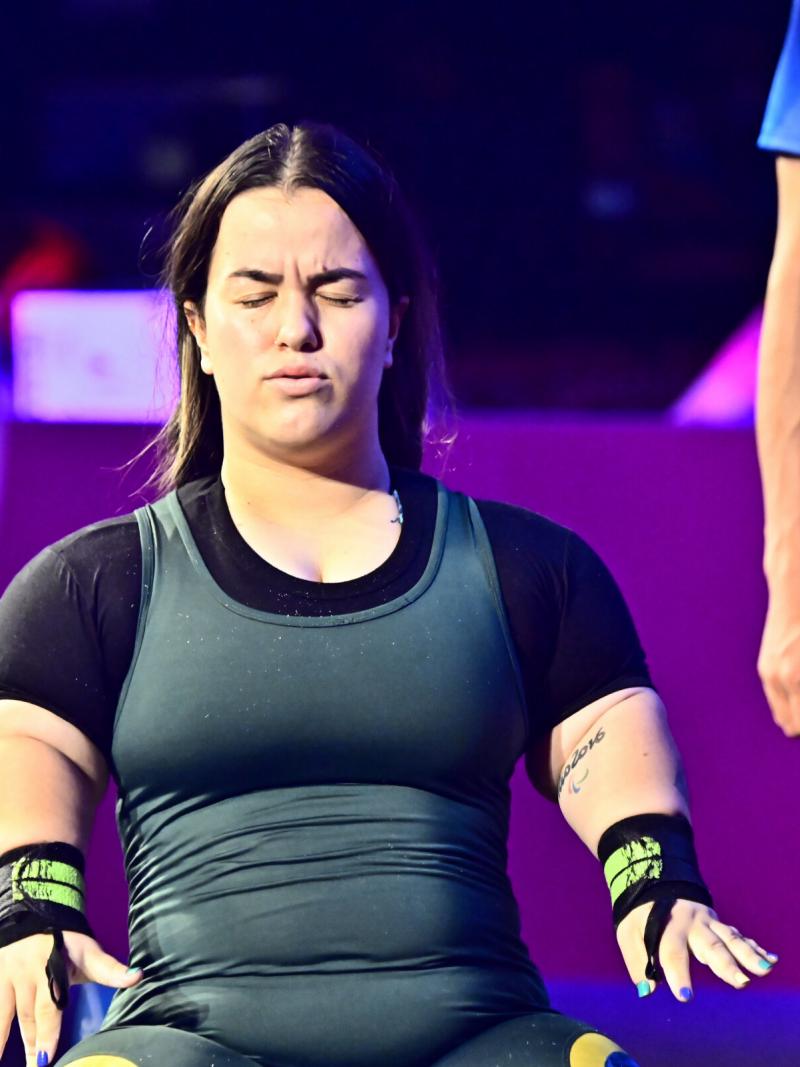 A woman standing with her eyes closed and her arms stretched with fists wide-open.