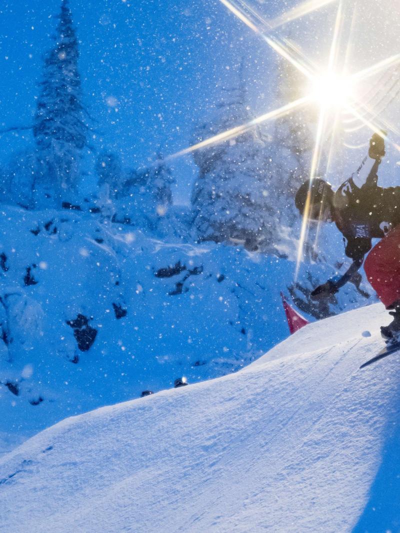 A female Para snowboarder riding on the snow with floodlights in the background