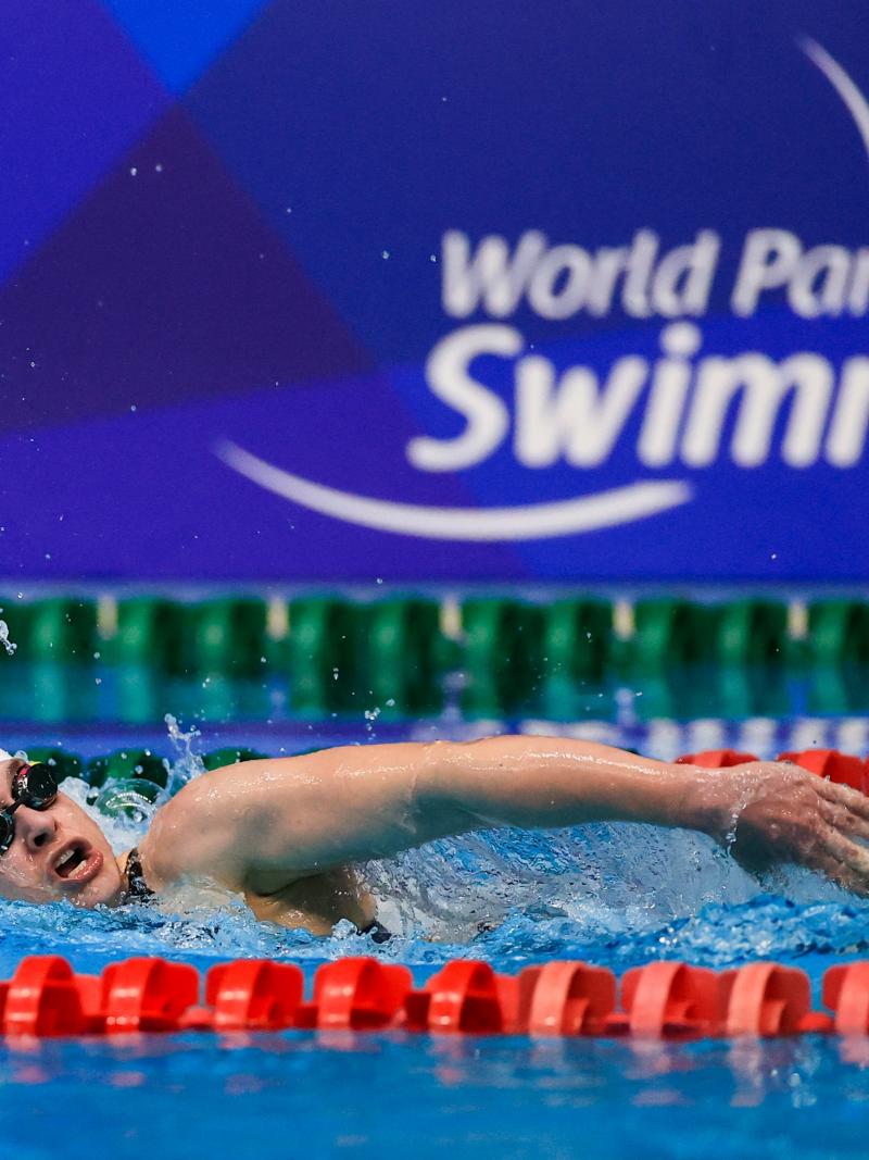 A female swimming in a pool with the logo of World Para Swimming on the background