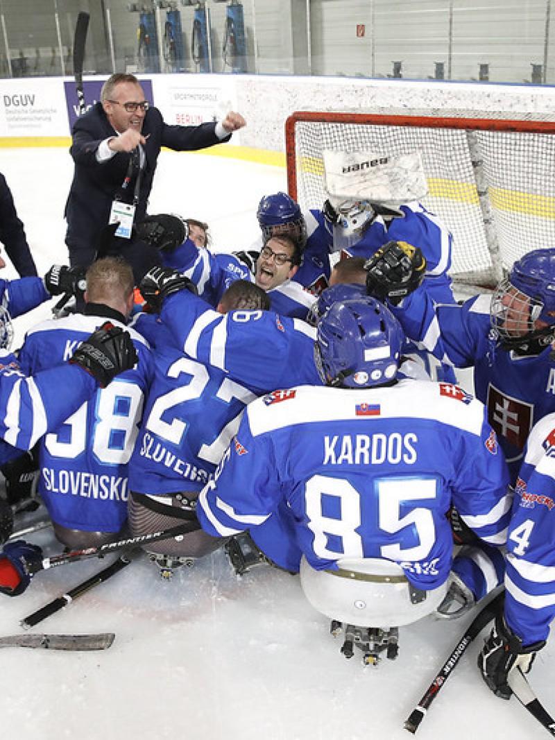 A group of Slovakian Para ice hockey players celebrating on an ice rink with four standing people
