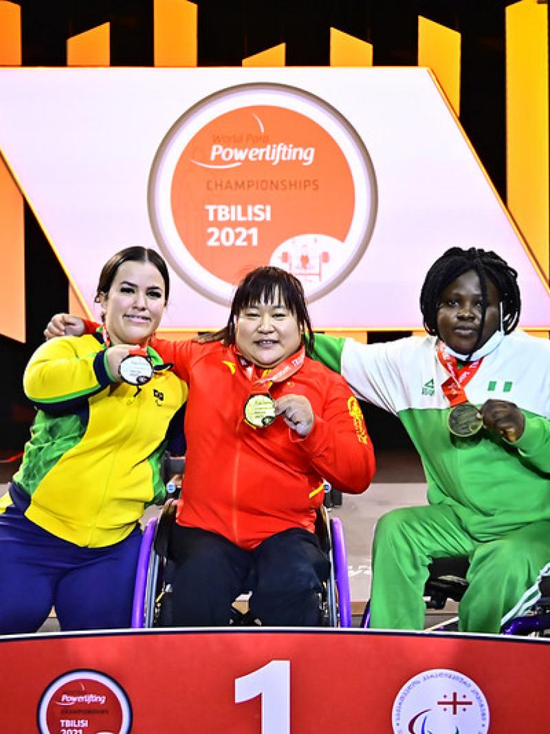 Three women on a podium showing their medals